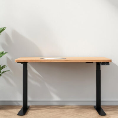 Drewniany blat wspiera się na czarnym, metalowym stelażu stołu obok zielonej rośliny.